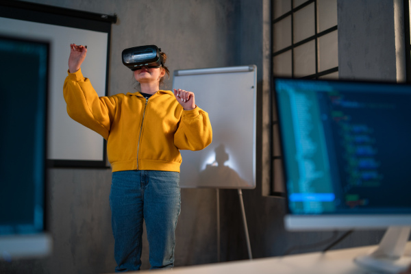 A schoolgirl wearing virtual reality goggles at school in computer science class