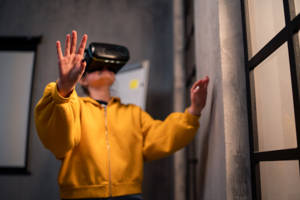 A schoolgirl wearing virtual reality goggles at school in computer science class