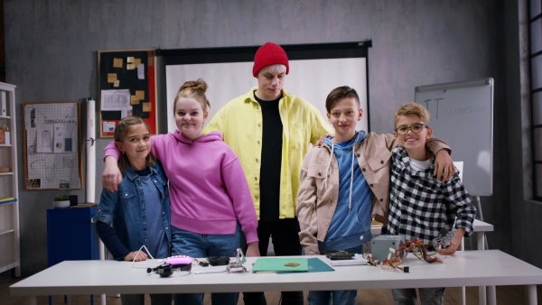 A group of happy kids with their science teacher with electric toys and robots at robotics classroom