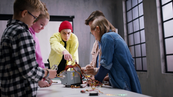 A group of happy kids with their science teacher with electric toys and robots at robotics classroom