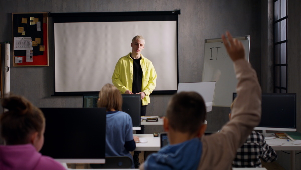 A teacher giving computer science lecture to young students in dark room. Room. Explaining Information Technology.