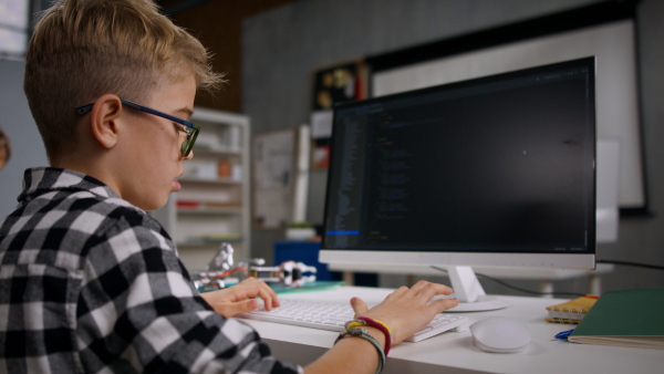 A schoolboy using computer in classroom at school