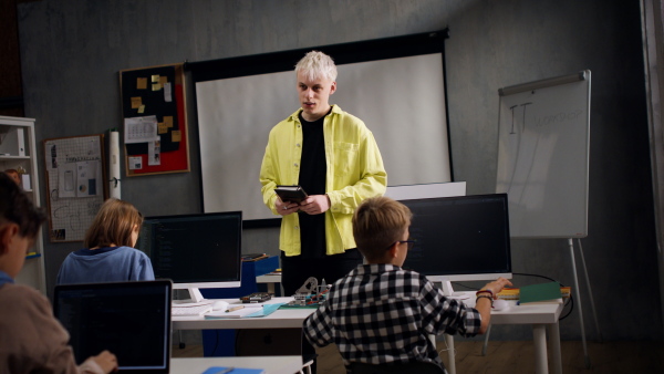 A teacher giving computer science lecture to young students in dark room. Room. Explaining Information Technology.