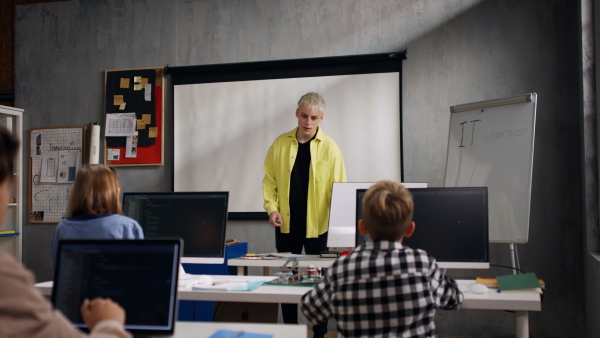 A teacher giving computer science lecture to young students in dark room. Room. Explaining Information Technology.