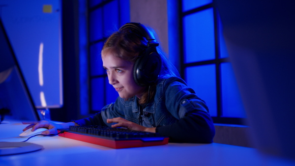 Young gamer girls with headphones playing a computer video game.