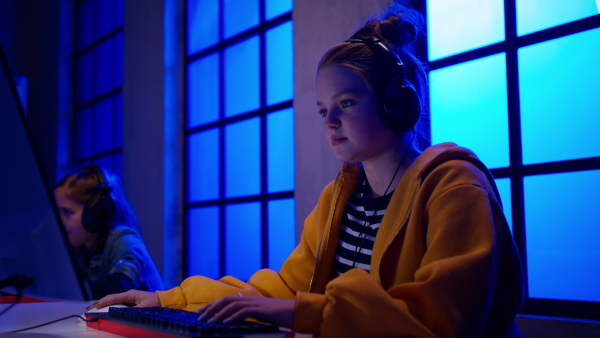 Young gamer girls with headphones playing a computer video game.