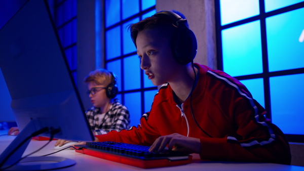 Young gamer boys with headphones playing a computer video game.