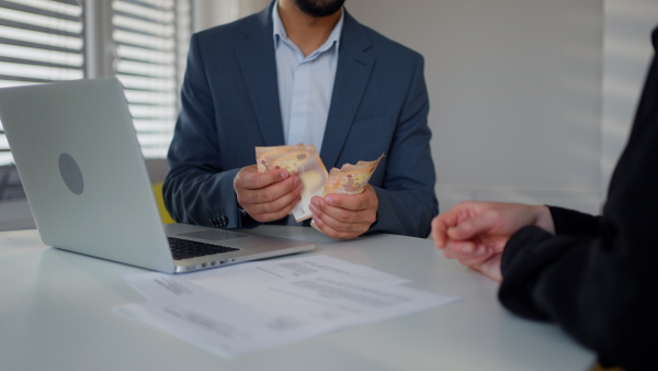 A businessman giving money to his partner while making contract - bribery and corruption concepts