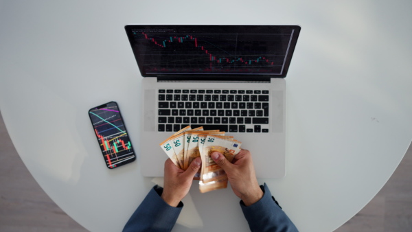 A businessman man counting euro money working on computer at office desk, inflation concept.