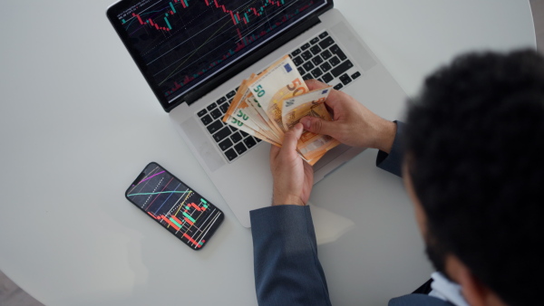 A businessman man counting euro money working on computer at office desk, inflation concept.