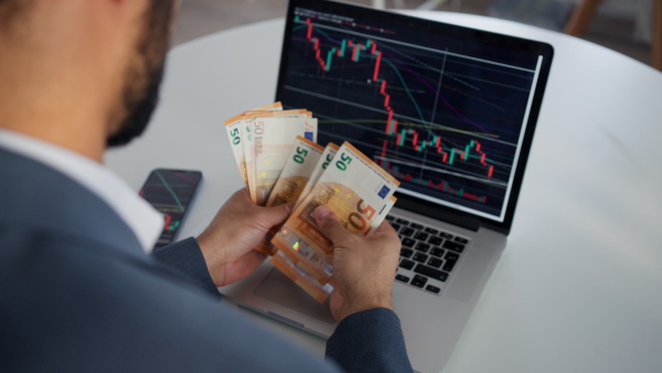 A businessman man counting euro money working on computer at office desk, inflation concept.