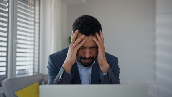 A depressed businessman man counting euro money working on computer at office desk, inflation concept.