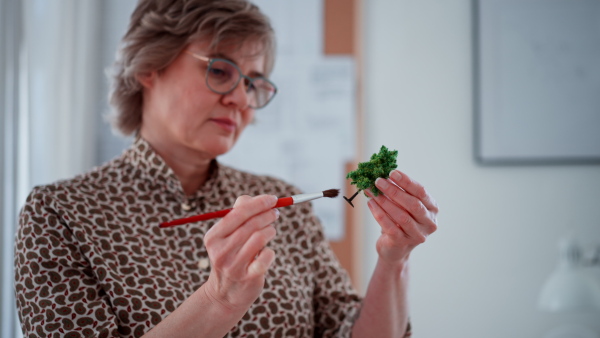 A senior woman eco architect with model of modern bulidings working in office.