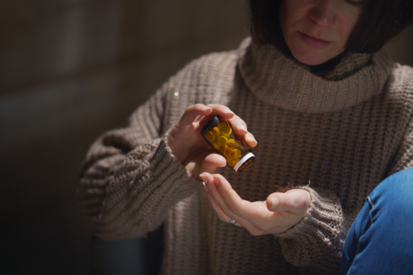 A depressed woman taking pills, mental health concept.