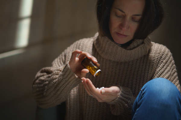 A depressed woman taking pills, mental health concept.