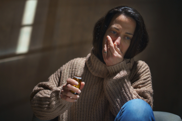 A depressed woman taking pills, mental health concept.