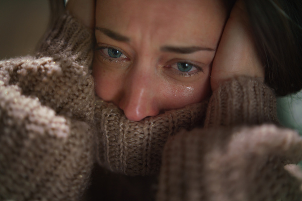 A close-up of depressed mid-adult lonely woman crying in the dark.