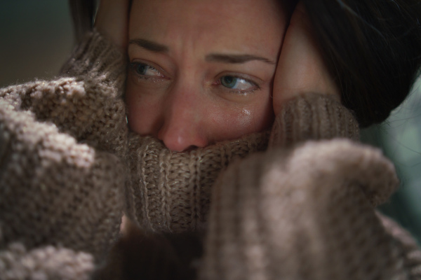 A close-up of depressed mid-adult lonely woman crying in the dark.