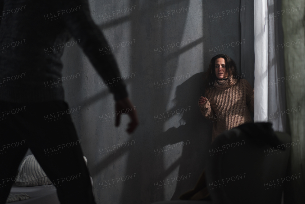 A scared woman sitting in corner with fear from her violent husband at home.