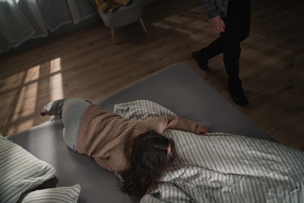 An overhead view of sad woman suffering from multiple personality disorders lying in bed.