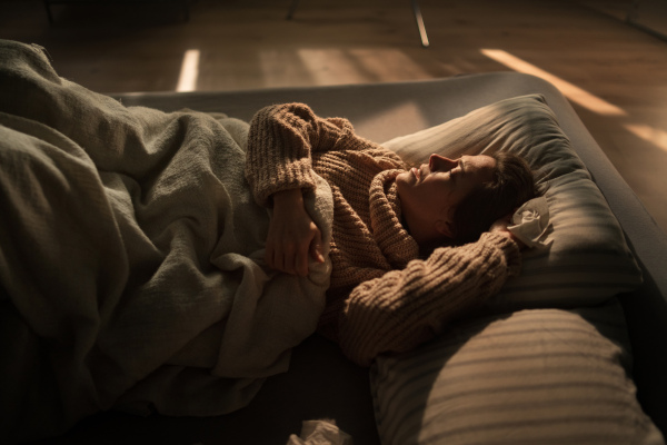 A close-up of sad woman suffering from covid depression lying in bed in night.