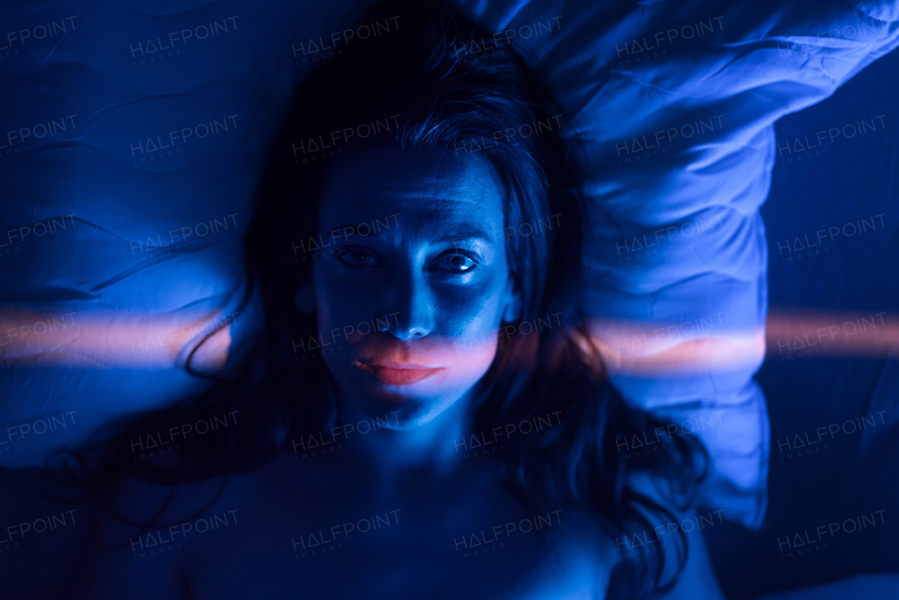 A close-up of lonely woman suffering from insomnia and depression, lying sleepless in bed at night.