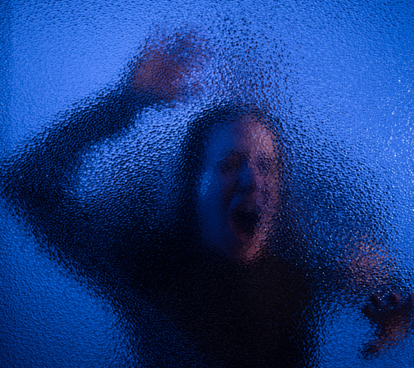 The shadow of woman screaming behind the glass, domestic violence concept.