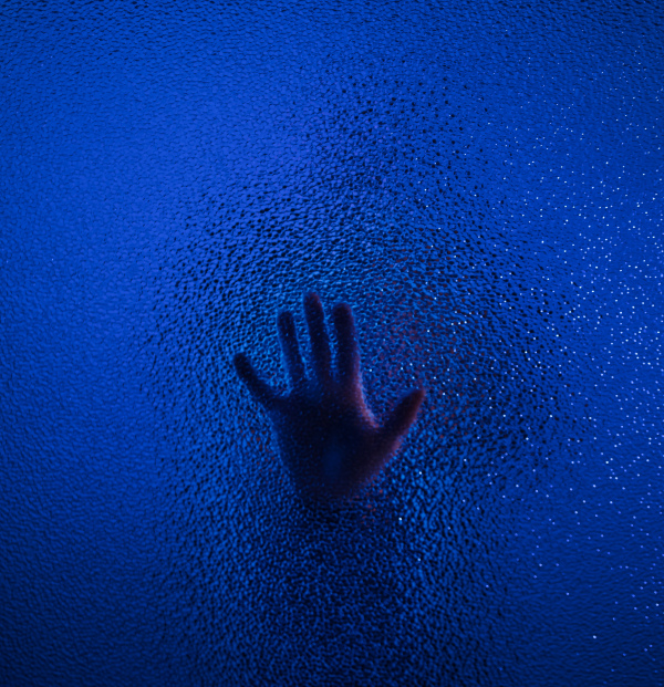 The shadow hand of a human behind the glass.