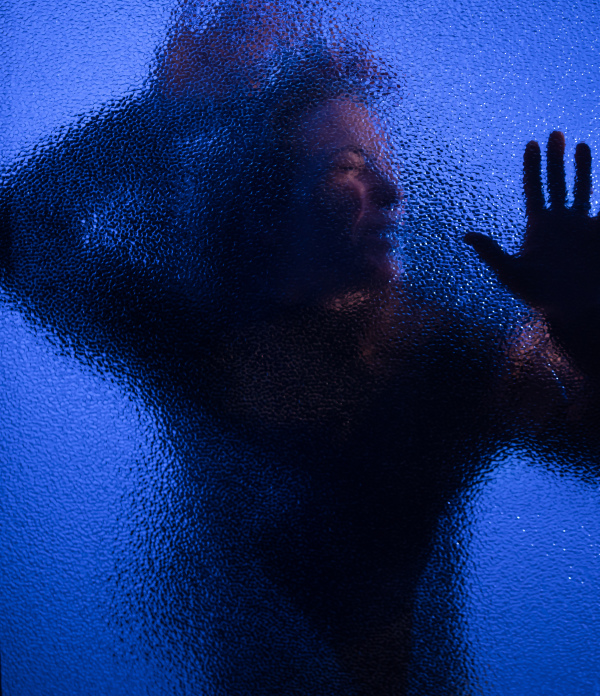 The shadow of woman screaming behind the glass, domestic violence concept.