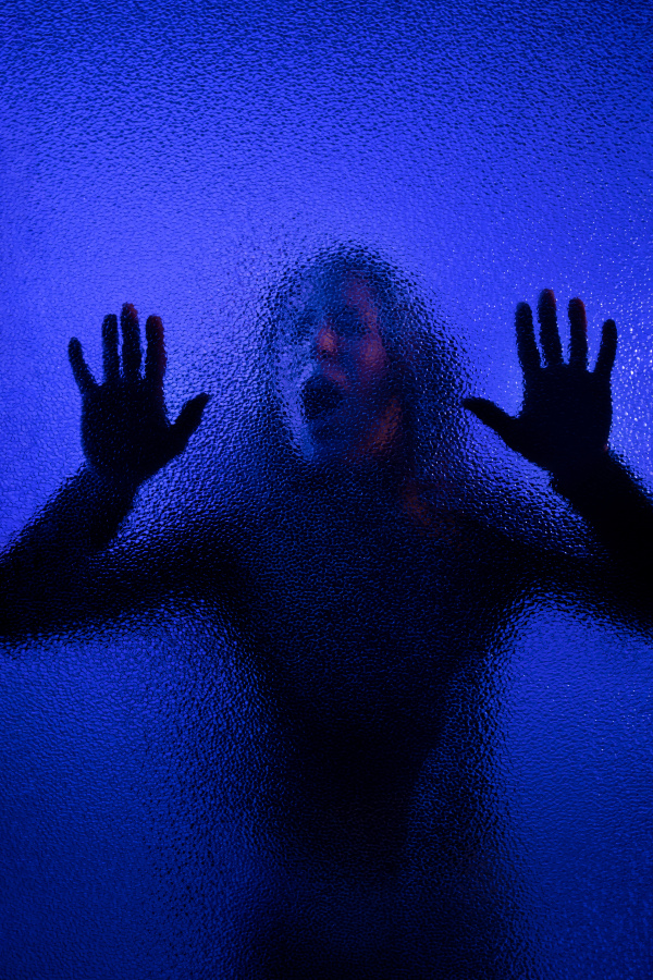 The shadow of woman screaming behind the glass, domestic violence concept.