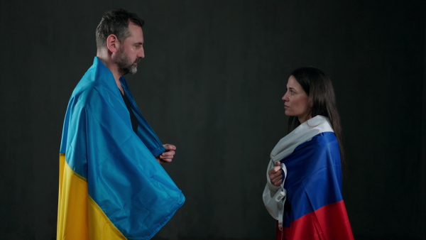 A man in Ukraine flag and woman in Russian flag in love hugging, cross-border love concept.