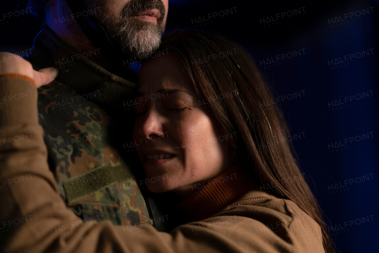 A sad woman crying when hugging her military husband and saying-goodby to him.