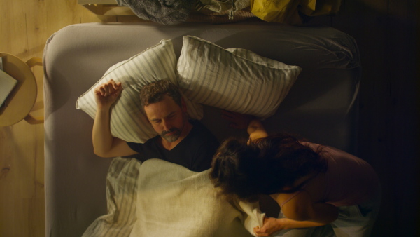 An overhead view of mid-adult couple lying in bed at night and hugging