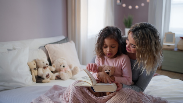 A happy mother hodling her little daughter and looking at each other in bed.