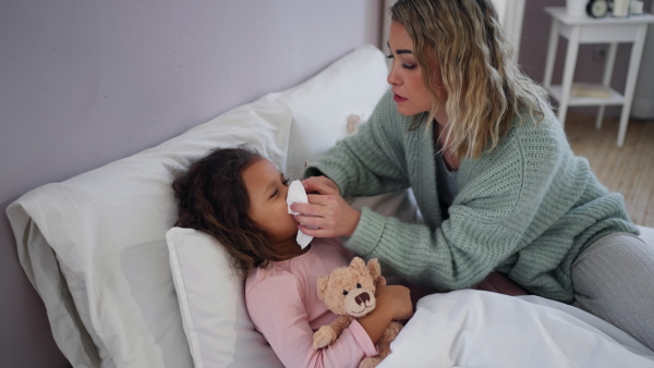 A mother taking care of her ill daughter at home.