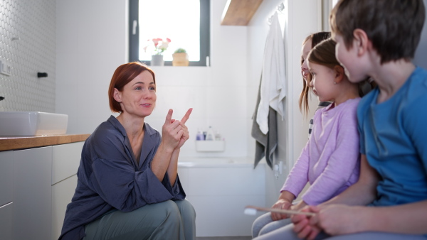 A mother with three little children in bathroom, morning routine concept.