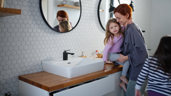 A mother combing her little daughter's hair in bathroom, morning routine concept.