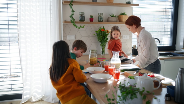 A mother of three little children preparing breakfast in kitchen at home.