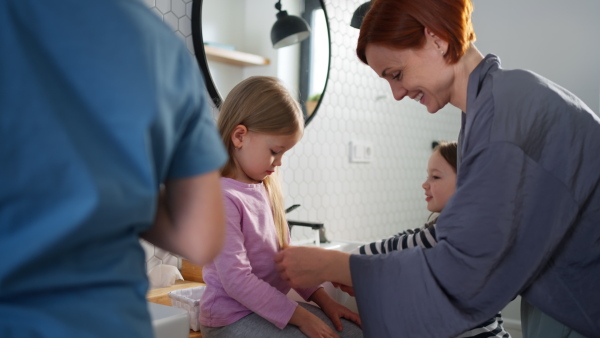 A mother with three little children in bathroom, morning routine concept.