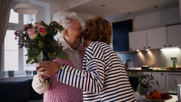 A happy mature woman surprising her senior mother when visiting her at home.