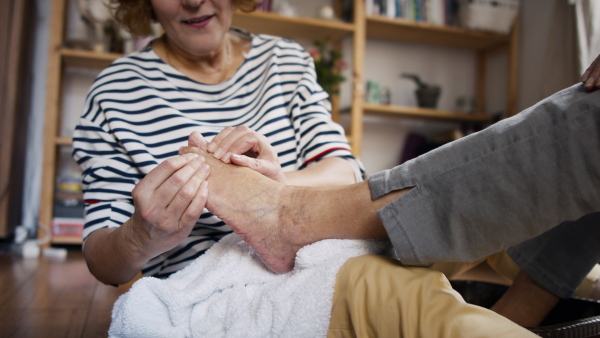 A senior woman getting foot massage from healthcare worker at home.