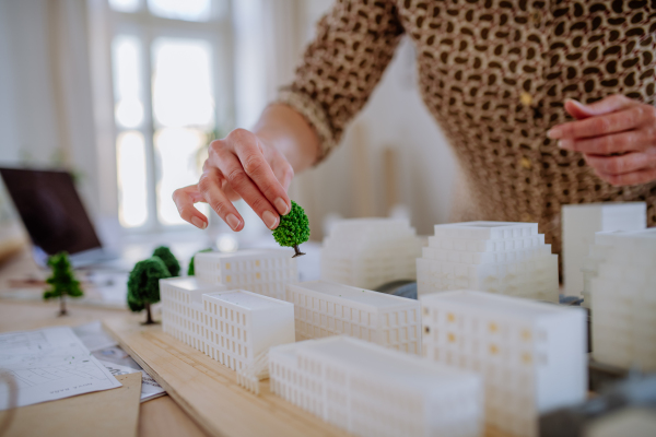 A close-up of woman architect with model of houses in office