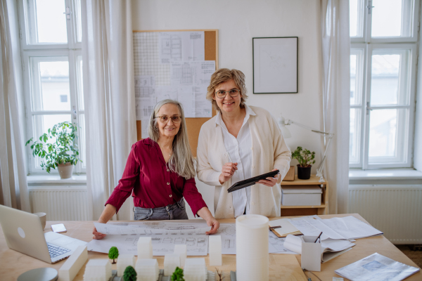 Mature women architects working together in an office, looking at camera.