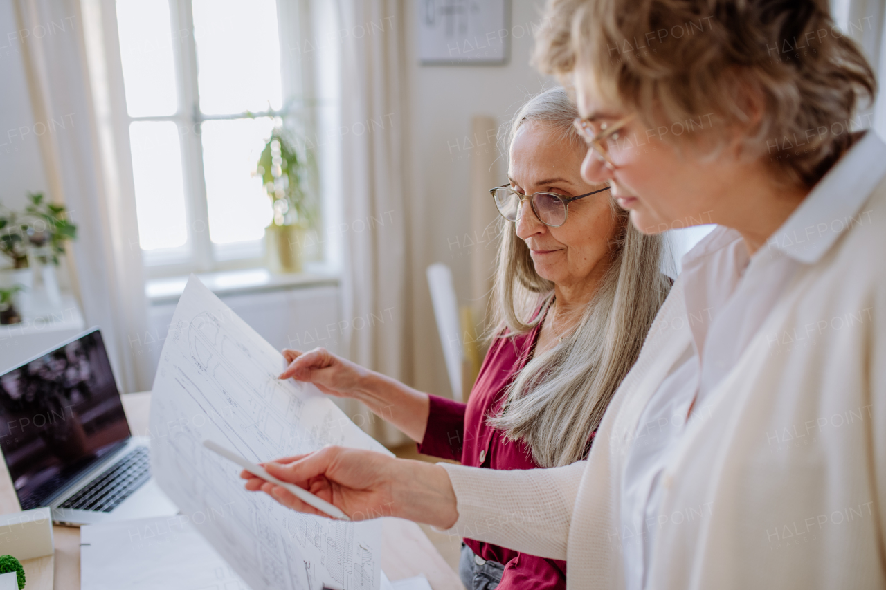 Senior women architects looking at the blueprints together in office .