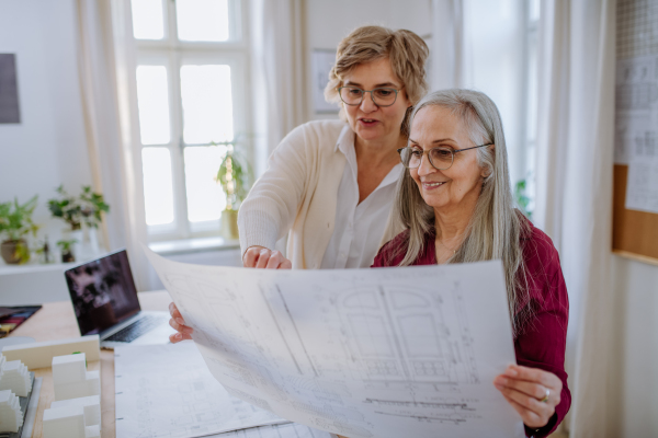 Senior women architects looking at the blueprints together in office .