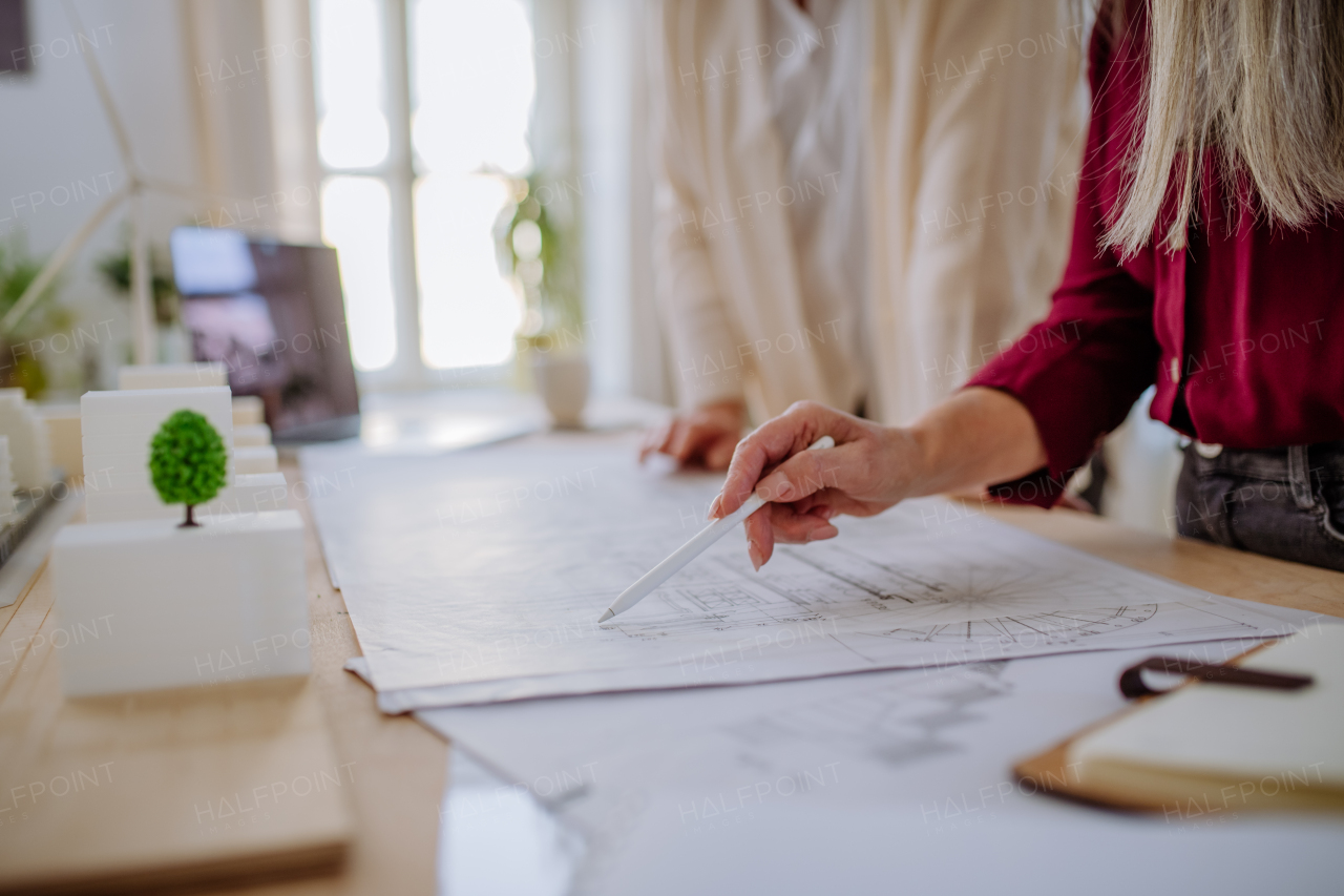 A close-up of woman architect looking at blueprints in office.