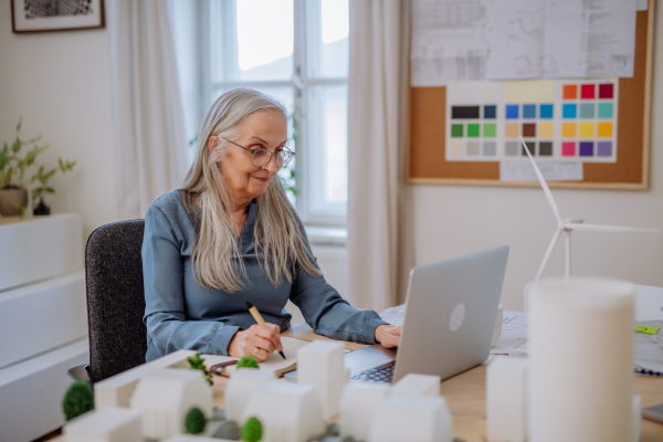 A senior woman eco architect working on lapotp in office.