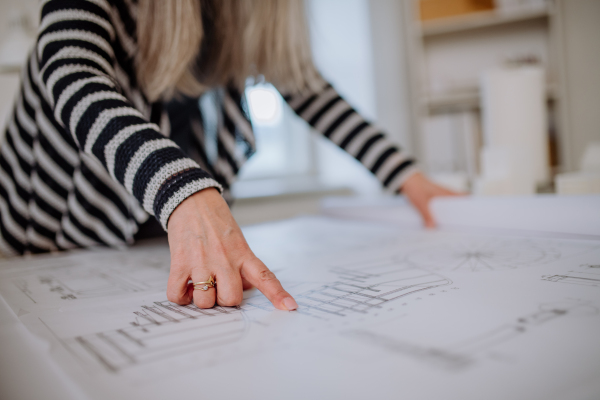 A close-up of woman architect looking at blueprints in office.