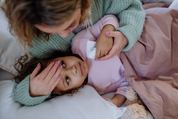 A mother taking care of her ill daughter at home.