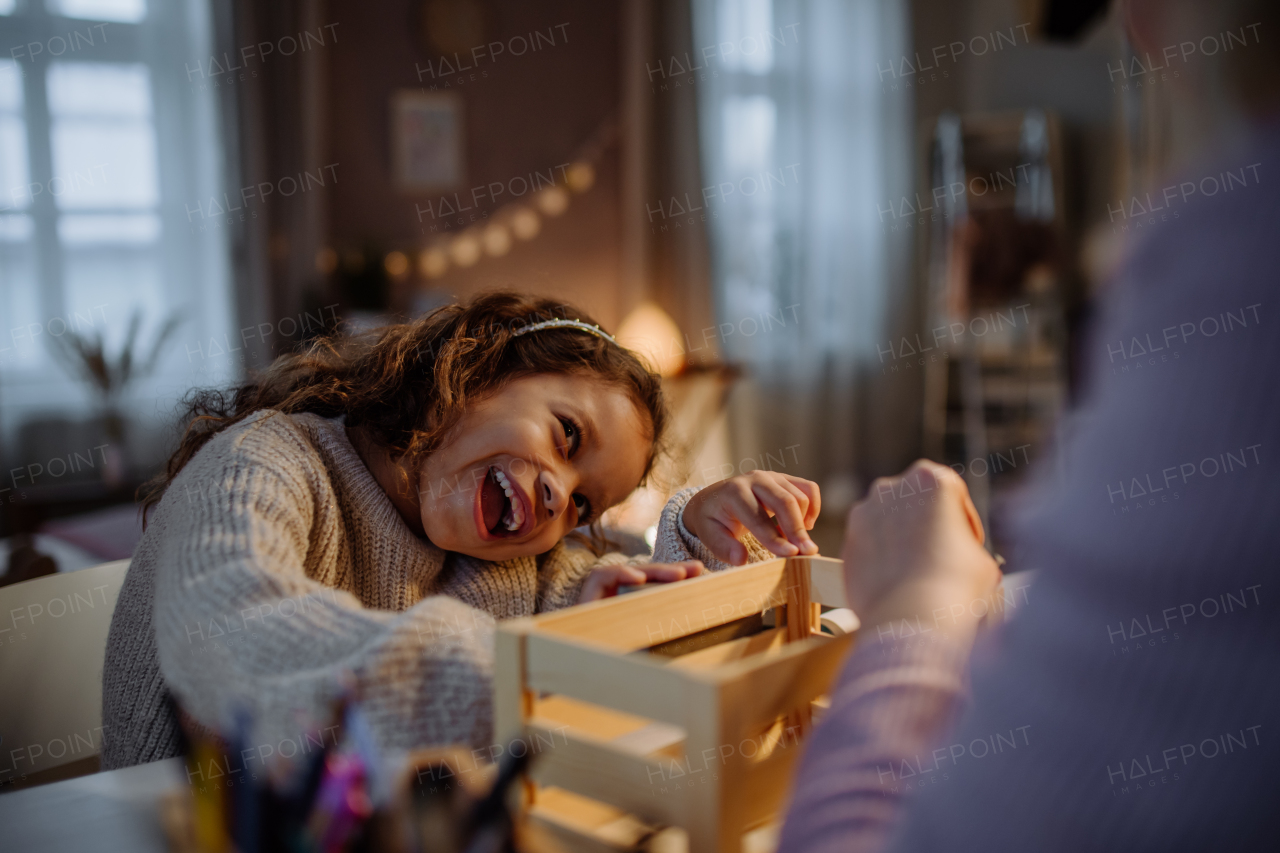 A happy little girl renovating a wooden crate together with her mother at home.